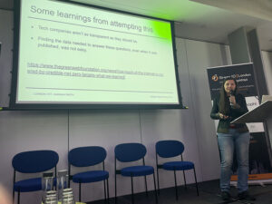 Hannah Smith on a stage with microphone in front of a side with text about lessons learned.
