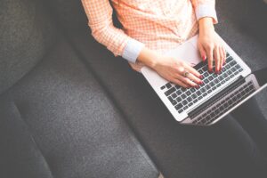 Looking down on a women sitting on a sofa using a laptop.